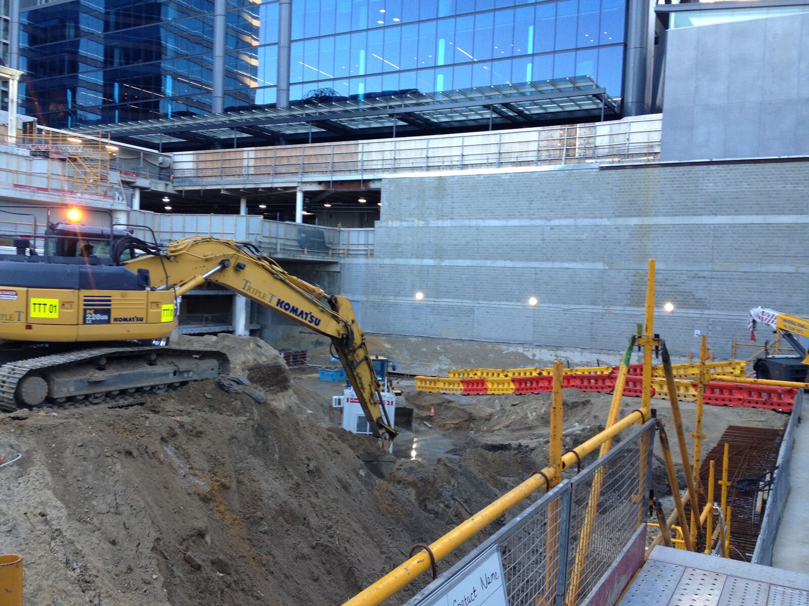 Excavator digging a basement beside a city tower under construction