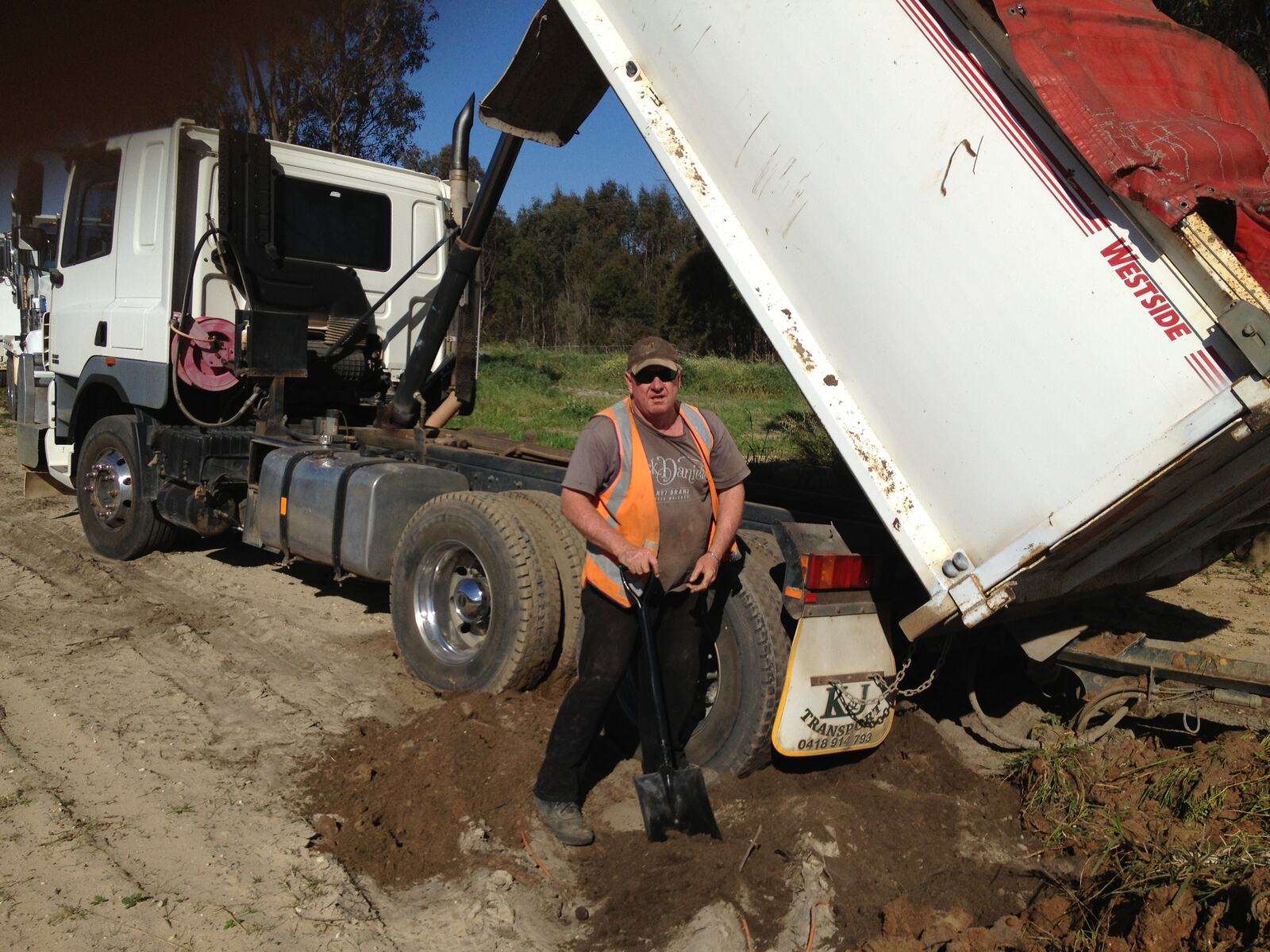 K & J driver in hi-vis beside a tipper unloading soil on a bush block