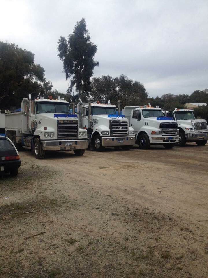 Row of white K & J Transport Macks parked in the yard