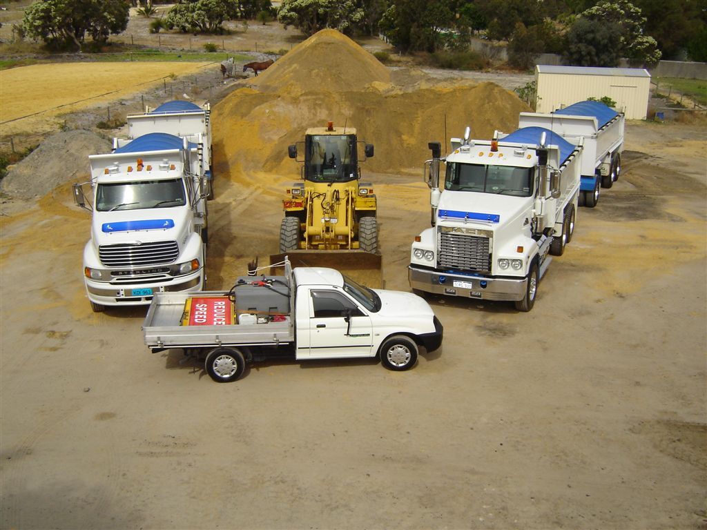 Loader beside a sand stockpile with trucks lined up to load