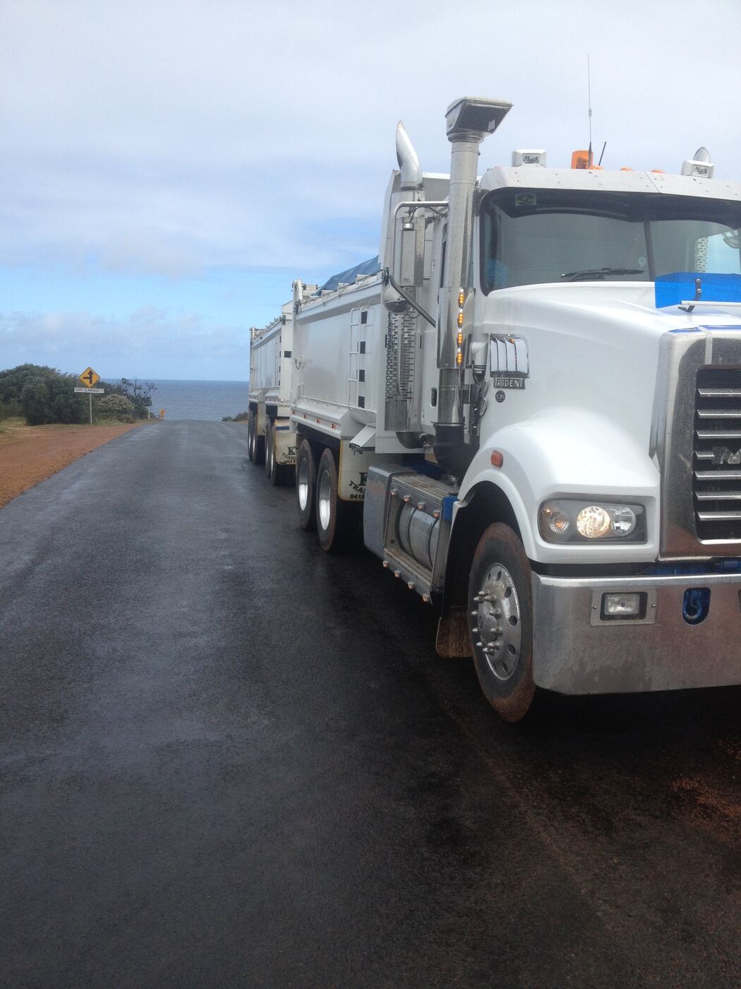 K & J Mack truck and dog on a wet coastal road