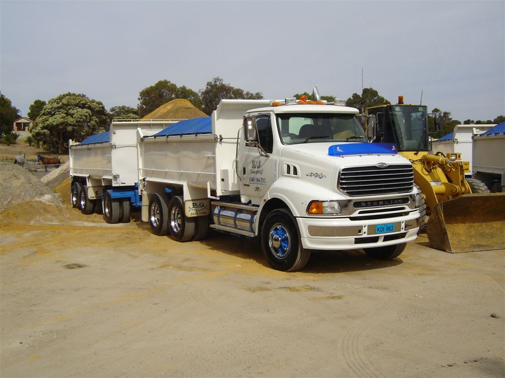 K & J trucks queued beside a loader at a sand pit