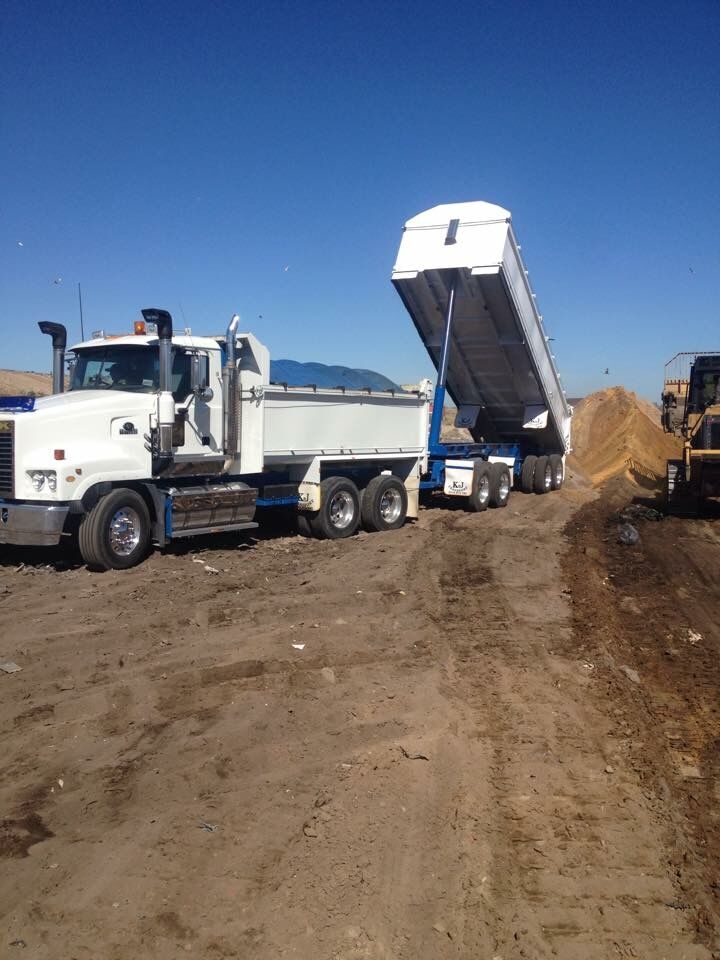 Truck and dog tipping a load of sand on a building site